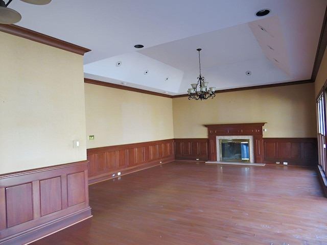 unfurnished living room with ornamental molding, dark hardwood / wood-style floors, a notable chandelier, and a raised ceiling