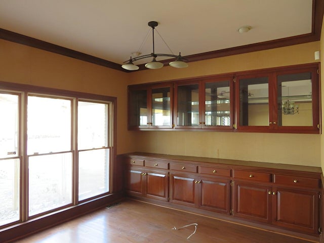 unfurnished dining area with hardwood / wood-style floors and crown molding