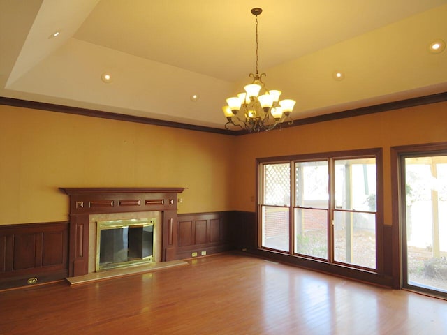 unfurnished living room with a raised ceiling, an inviting chandelier, and wood-type flooring