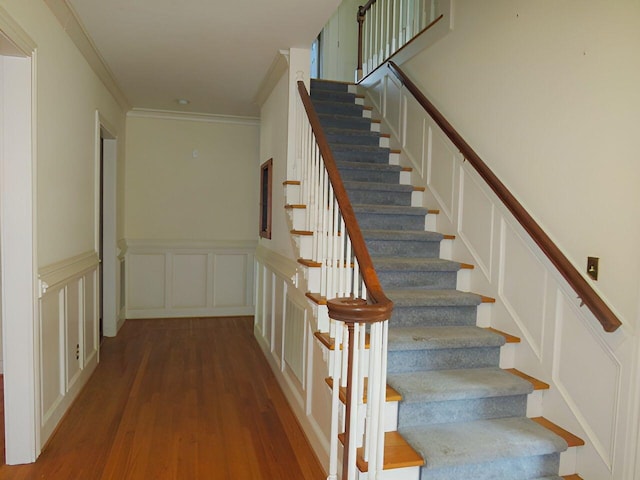 stairs featuring hardwood / wood-style flooring and ornamental molding