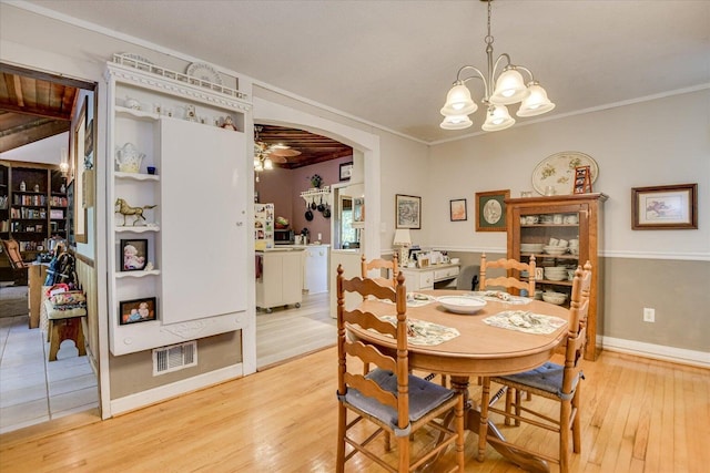 889 Woodhaven St, North, SC 29112 - dining space with light wood-style floors, a chandelier, crown molding, and arched walkways