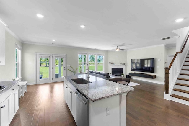 kitchen featuring a sink, stainless steel dishwasher, crown molding, ceiling fan, and a fireplace