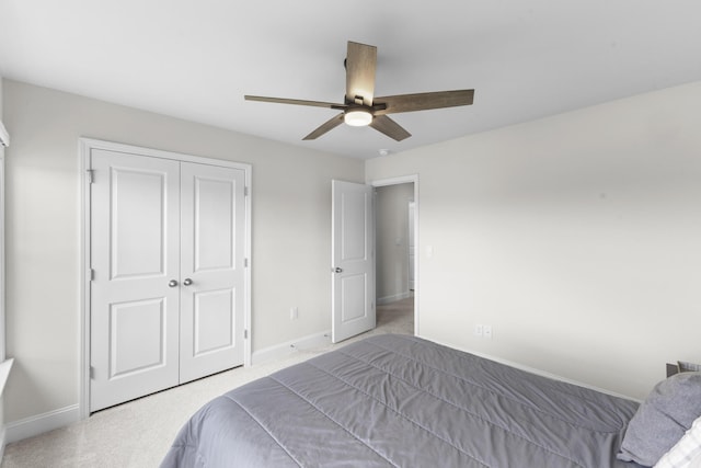 carpeted bedroom with a closet, baseboards, and a ceiling fan