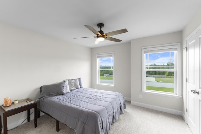 bedroom with baseboards, light colored carpet, and a ceiling fan