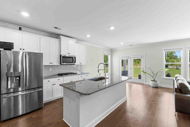 kitchen featuring stainless steel appliances, a sink, stone counters, white cabinetry, and decorative backsplash