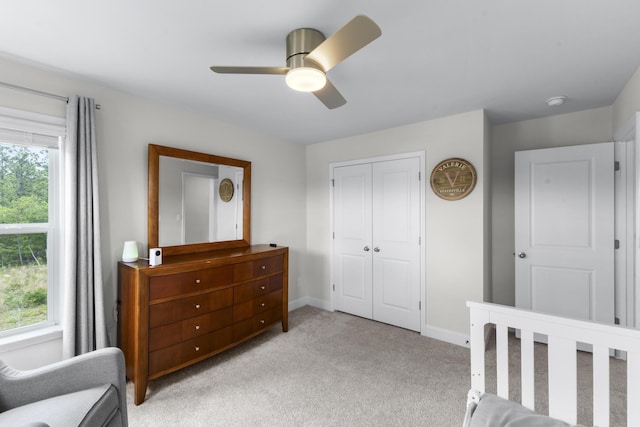 bedroom featuring light carpet, a closet, baseboards, and a ceiling fan