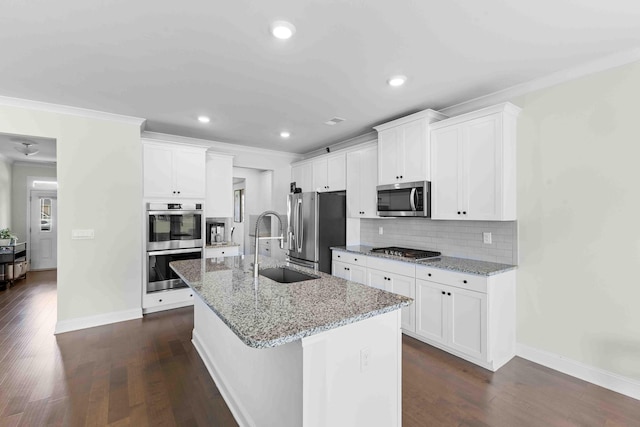 kitchen featuring stainless steel appliances, a sink, a kitchen island with sink, baseboards, and crown molding