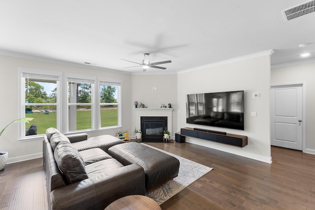 living room featuring baseboards, crown molding, wood finished floors, ceiling fan, and a glass covered fireplace