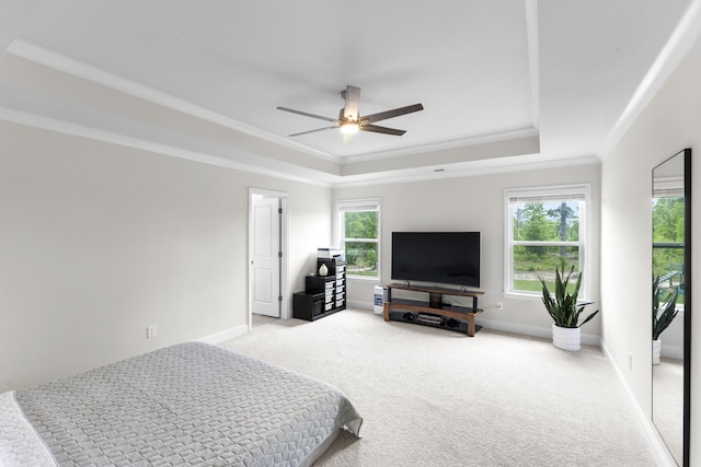 bedroom with a tray ceiling, carpet flooring, crown molding, baseboards, and ceiling fan