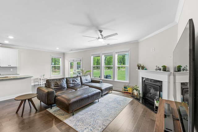 living area with ornamental molding, a ceiling fan, a premium fireplace, recessed lighting, and dark wood finished floors