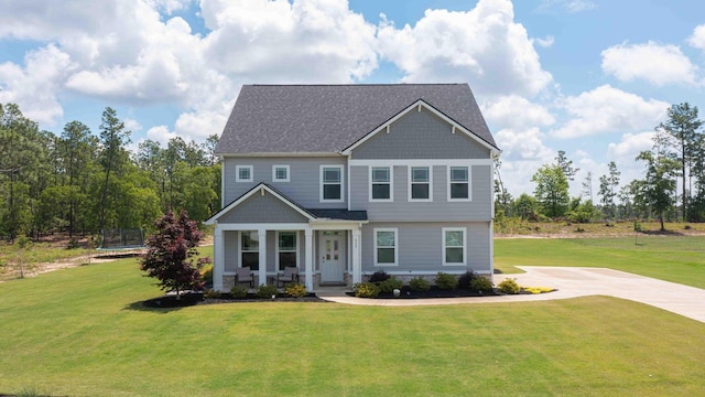 craftsman-style house featuring a trampoline, a front yard, a porch, and driveway