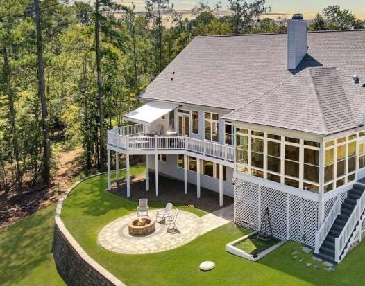 back of property with a lawn, a patio, and a fire pit