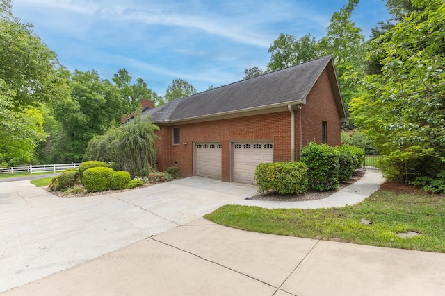 165 Indian Valley Ln, Swansea, SC 29160 - view of side of home with brick siding, concrete driveway, an attached garage, a chimney, and a shingled roof