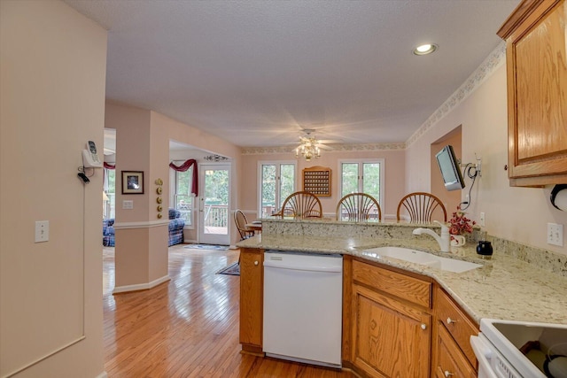 kitchen with kitchen peninsula, white dishwasher, ceiling fan, and sink