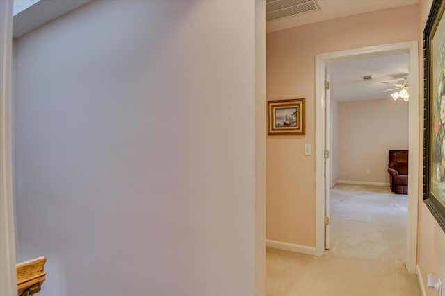 hall with light colored carpet and a textured ceiling