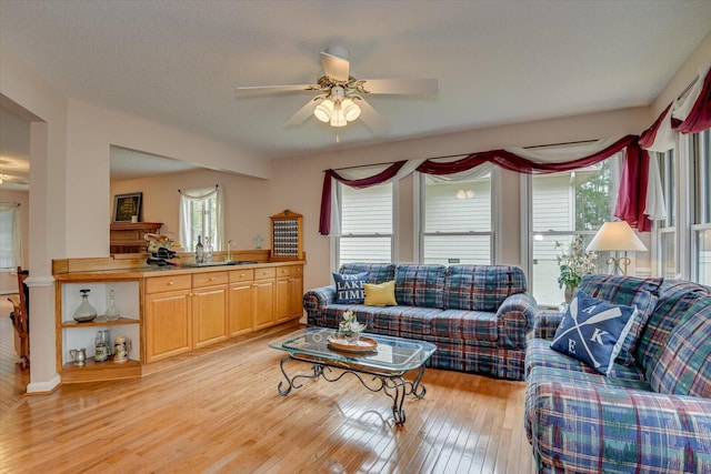 living room with ceiling fan, plenty of natural light, light hardwood / wood-style floors, and a textured ceiling