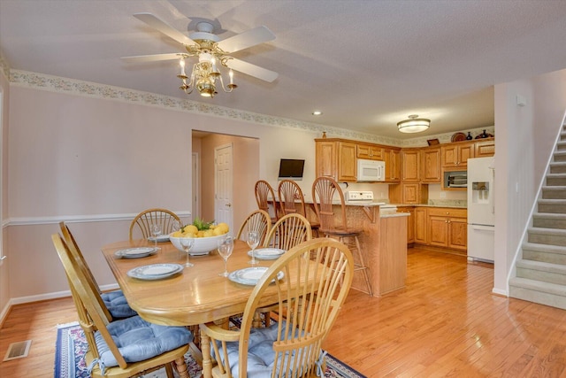 dining area with ceiling fan, a textured ceiling, and light wood-type flooring