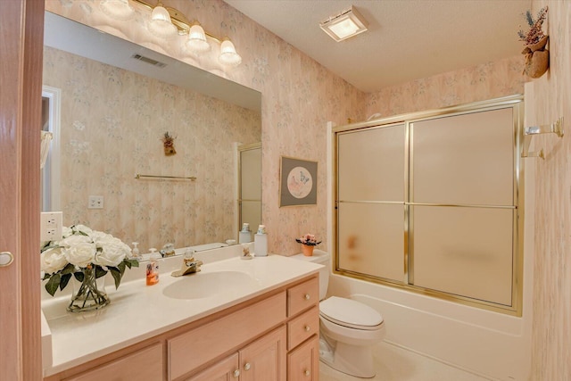 full bathroom with tile patterned flooring, bath / shower combo with glass door, a textured ceiling, toilet, and vanity