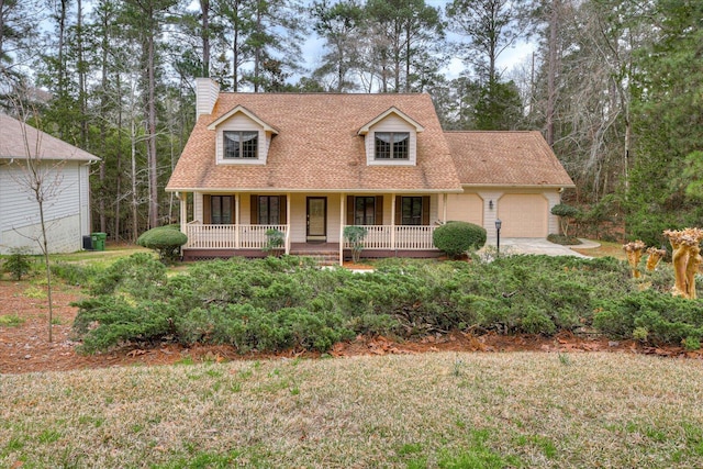 new england style home featuring a front yard, a porch, and a garage