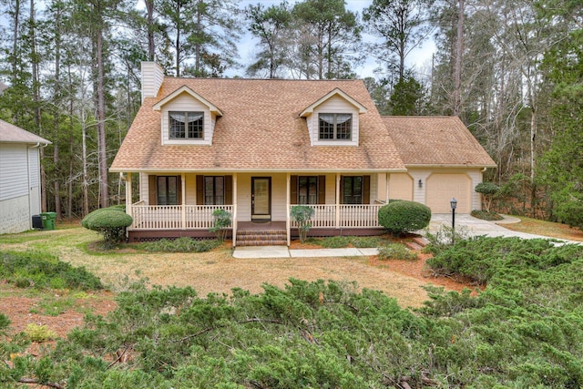 cape cod home featuring a front yard, a porch, and a garage