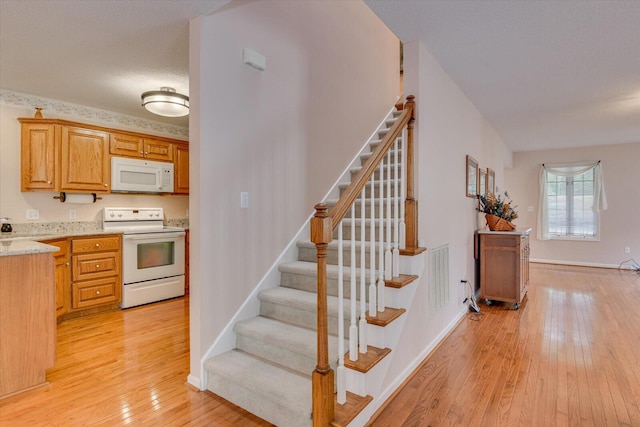 stairway with wood-type flooring and a textured ceiling