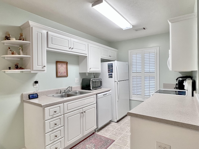 kitchen with a textured ceiling, white cabinetry, sink, and white appliances