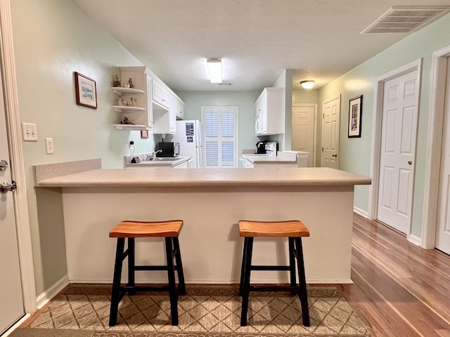 kitchen featuring white cabinets, a breakfast bar, kitchen peninsula, and electric stove