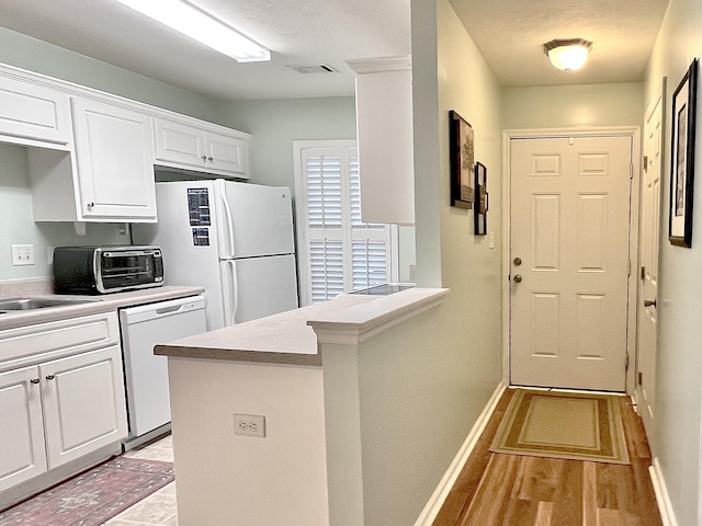 kitchen with white cabinetry, sink, white appliances, and kitchen peninsula