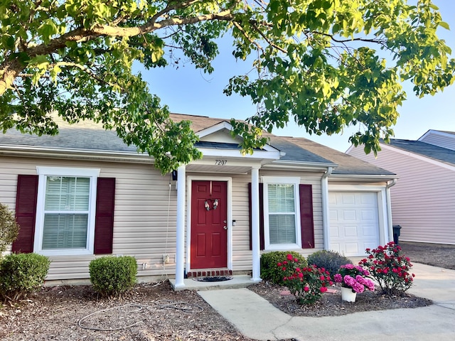 view of front of property featuring an attached garage and a shingled roof