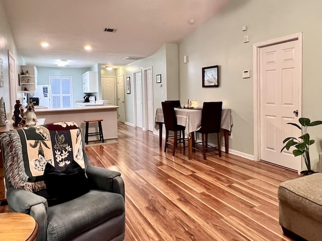 living area featuring visible vents, light wood-style flooring, recessed lighting, and baseboards