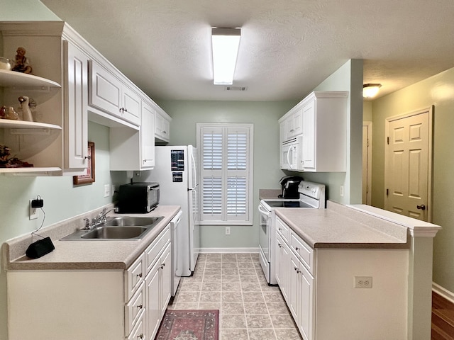 kitchen with white cabinetry, sink, kitchen peninsula, a textured ceiling, and white appliances