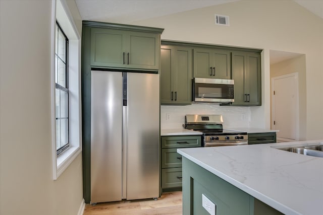 3022 Shady Ln, Hephzibah, GA 30815 - kitchen featuring green cabinetry, stainless steel appliances, light stone counters, light wood-type flooring, and lofted ceiling