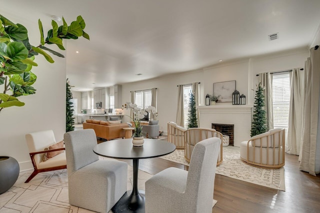 dining area with a wealth of natural light, a fireplace, and light wood-type flooring