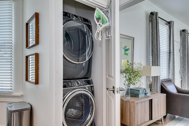 laundry room with ornamental molding and stacked washer / drying machine