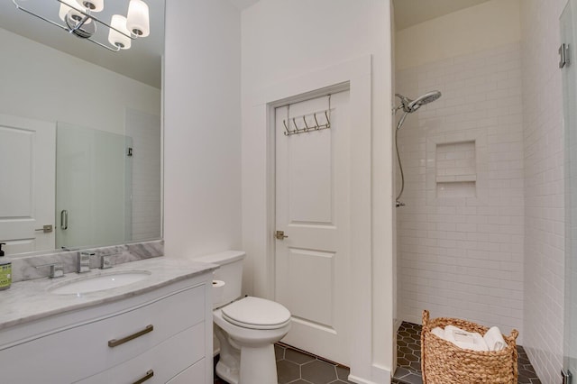 bathroom with tiled shower, vanity, tile patterned floors, and toilet