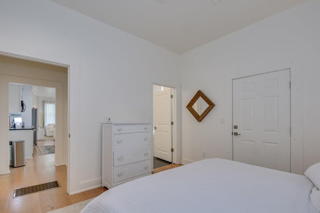 bedroom featuring stainless steel fridge, light hardwood / wood-style flooring, and a closet