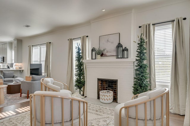 living room featuring a fireplace, light wood-type flooring, and crown molding