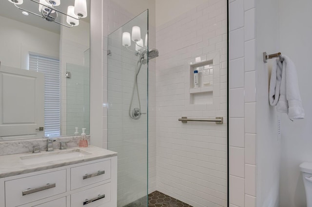 bathroom featuring tiled shower, vanity, an inviting chandelier, and toilet