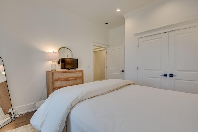 bedroom with hardwood / wood-style floors, crown molding, and a closet