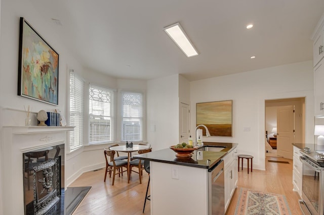 kitchen featuring a kitchen bar, stainless steel appliances, a kitchen island with sink, sink, and white cabinetry