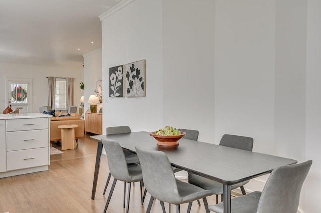 dining area with light wood-type flooring and ornamental molding