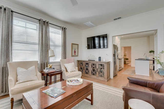 living room featuring sink, light hardwood / wood-style floors, and ornamental molding