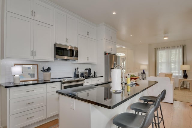 kitchen with white cabinetry, a center island with sink, and stainless steel appliances