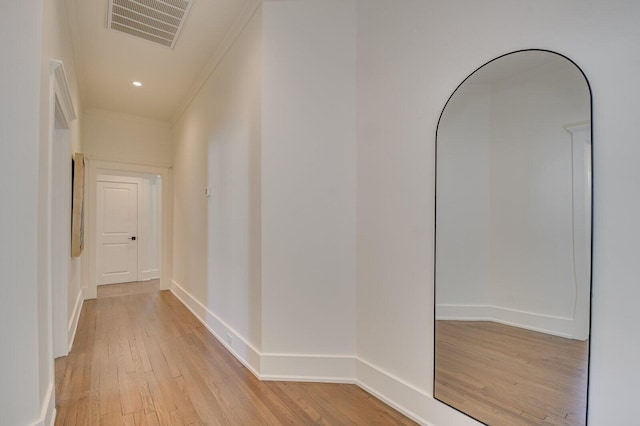 corridor with light hardwood / wood-style floors and ornamental molding