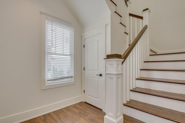 stairway with hardwood / wood-style flooring and lofted ceiling