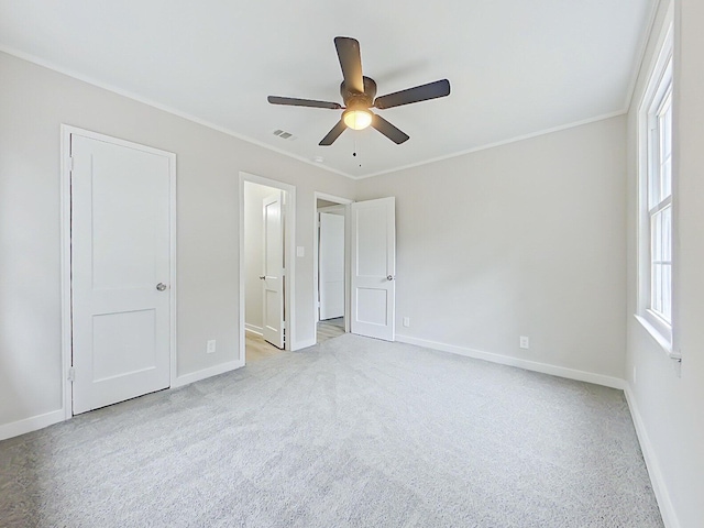 unfurnished bedroom with ceiling fan, light colored carpet, ornamental molding, and ensuite bathroom