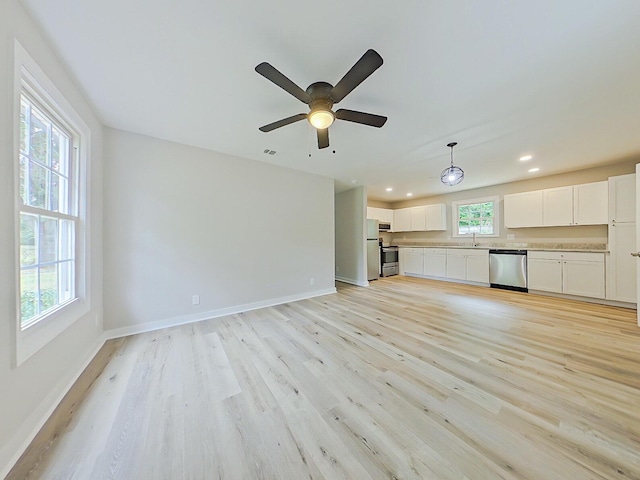 unfurnished living room featuring ceiling fan, a healthy amount of sunlight, and light hardwood / wood-style flooring