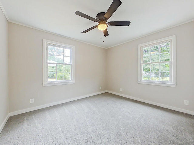 carpeted spare room featuring ceiling fan, plenty of natural light, and ornamental molding