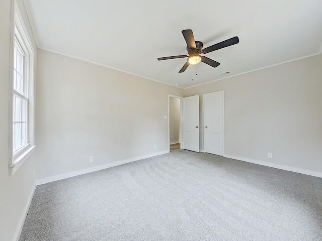 carpeted empty room with ceiling fan and crown molding