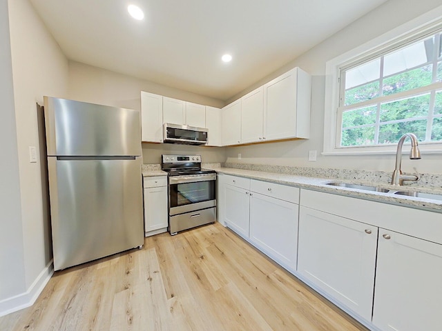 kitchen featuring appliances with stainless steel finishes, light hardwood / wood-style flooring, white cabinetry, and sink